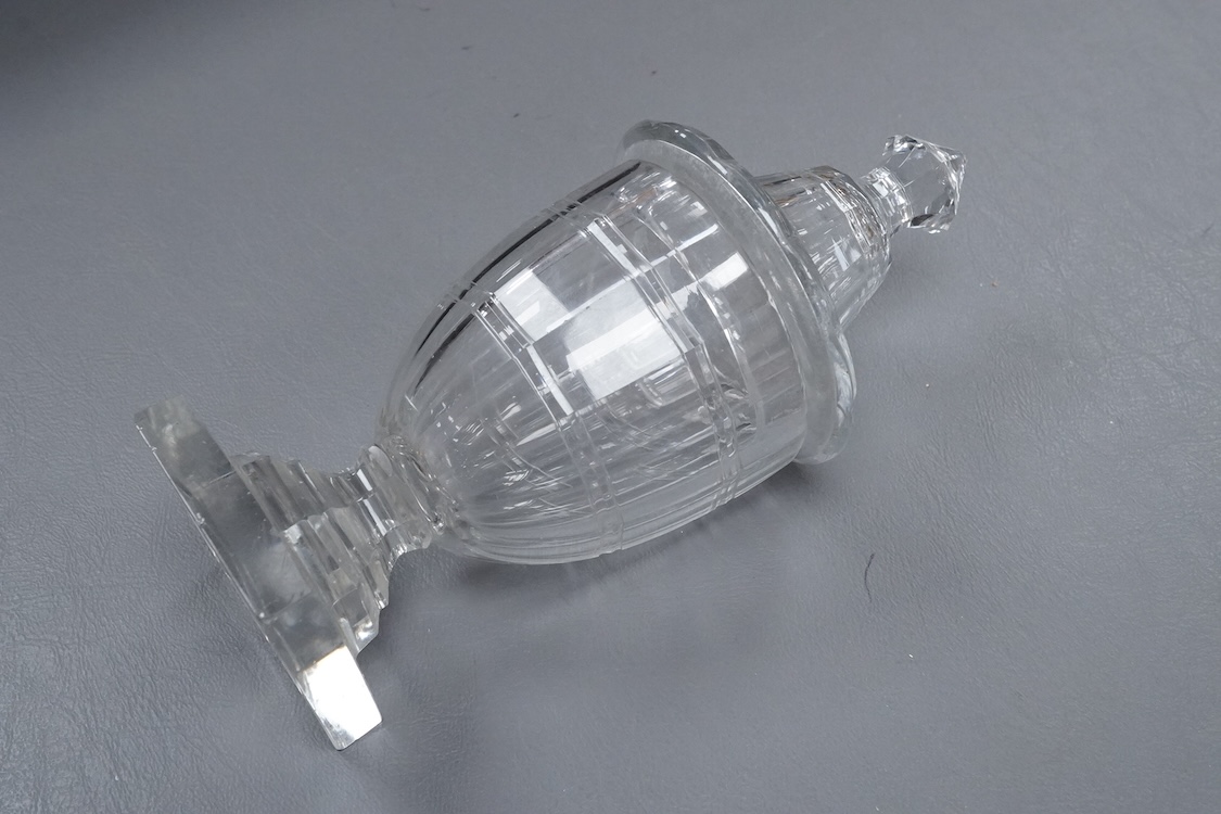 An early 19th century cut glass sweetmeat glass and cover in the shape of an urn, raised on a square pedestal base, with cut out for a spoon to the lid, 21cm high